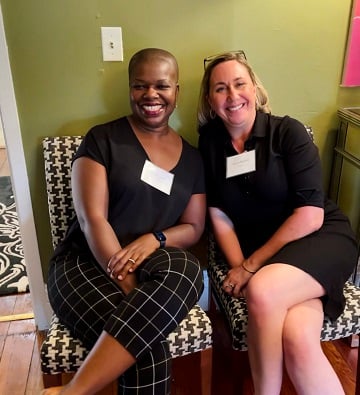 two women sitting down and smiling